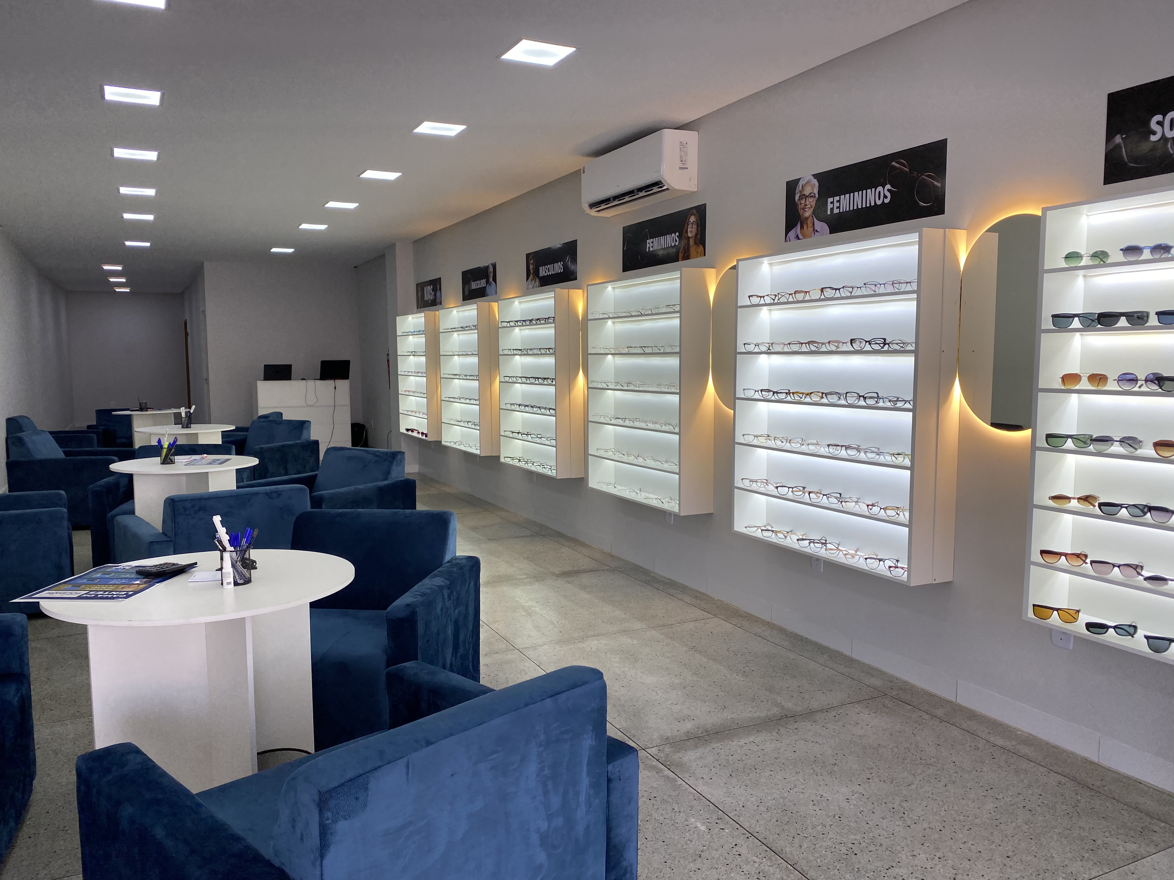 Interior da Óticas Solidare - Ambiente moderno com poltronas azuis e ampla variedade de óculos